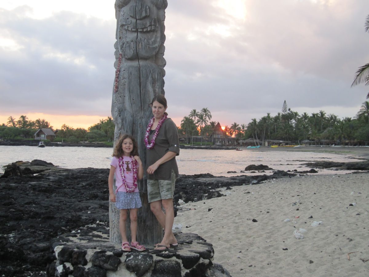 Mom and child in front of tiki on beach at sunrise