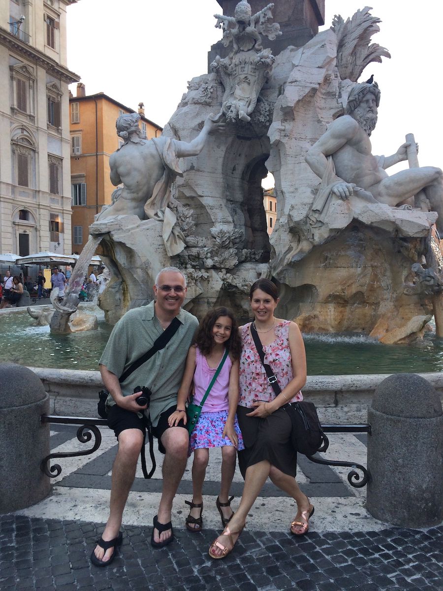 Family sitting at the fountain of the four rivers in Piazza Navona