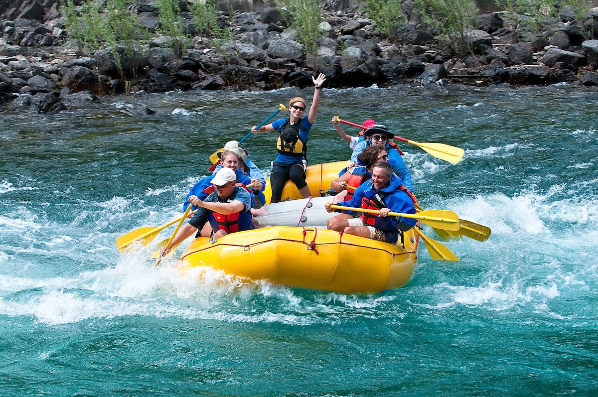 Yellow raft with passengers on river paddling through rapids image courtesy of GCT