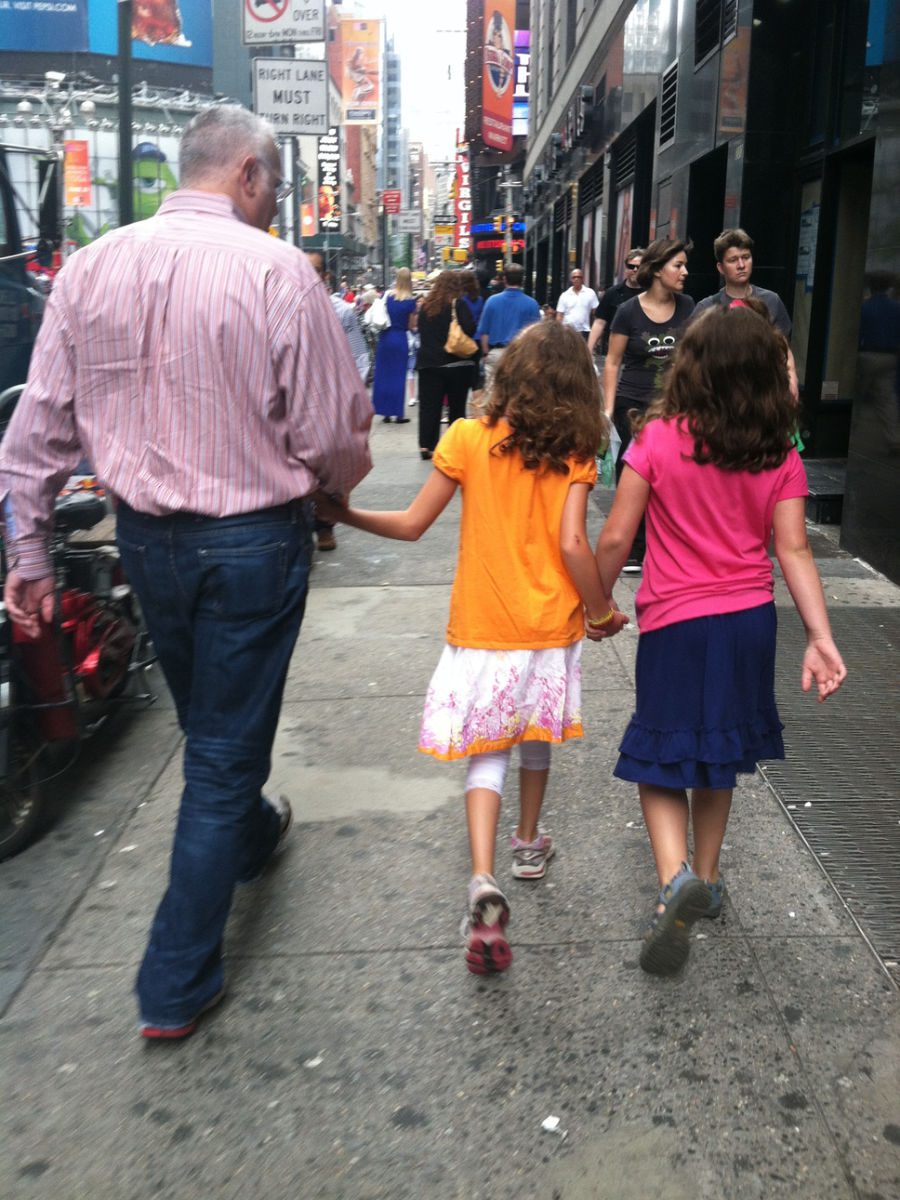 Man walking with two girls holding hands down street in new york city
