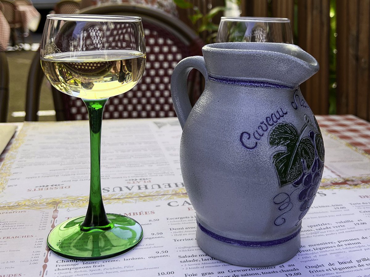 White wine in green stem glass next to pottery jug