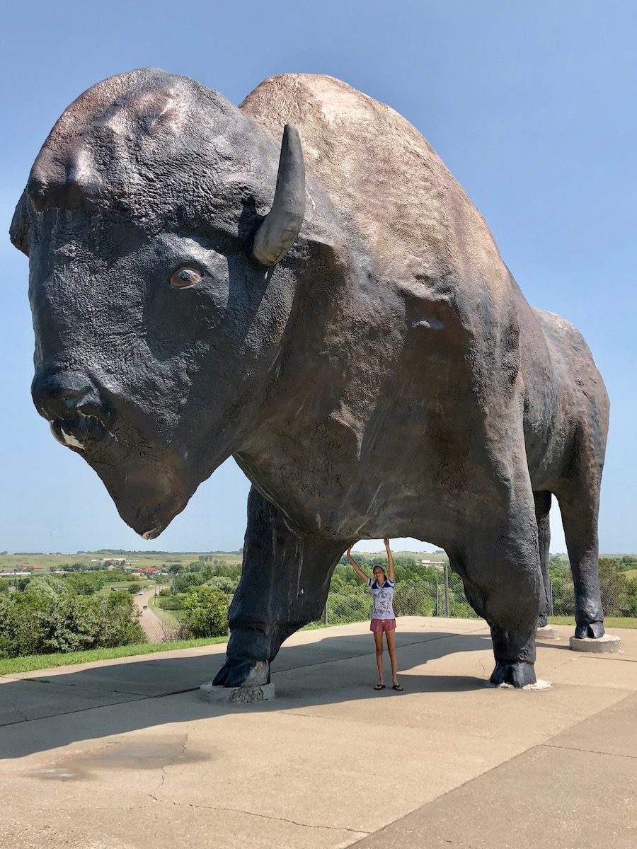 Girl standing under the World's Largest buffalo statue