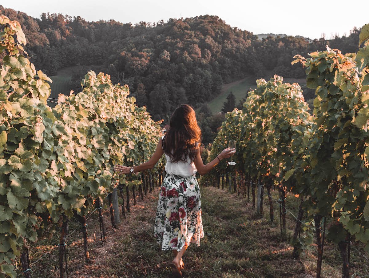 Woman walking through vineyard holding glass from Inspired by Croatia