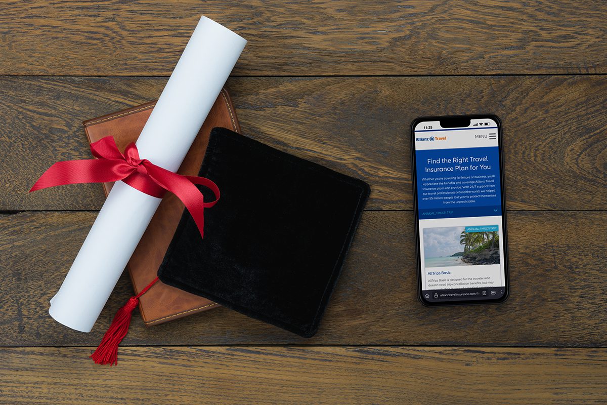 Graduation cap and diploma with Allianz Travel insurance website on phone