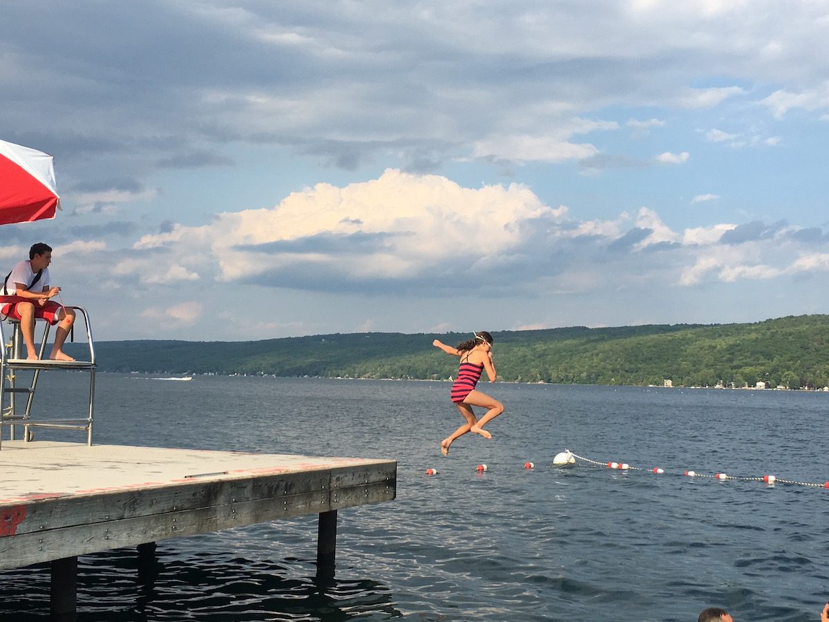 girl jumping into Keuka Lake