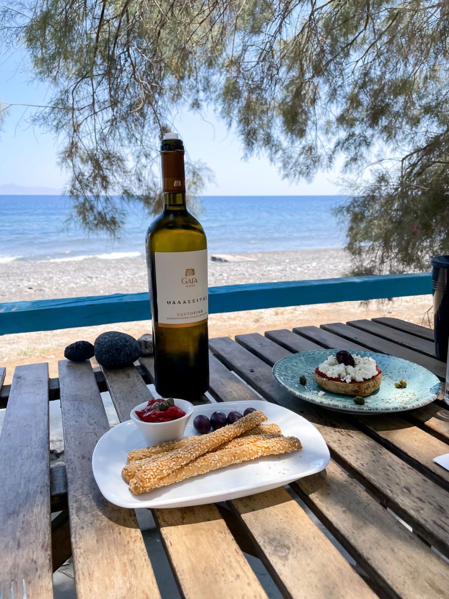 wine bottle and snacks overlooking the beach in Santorini