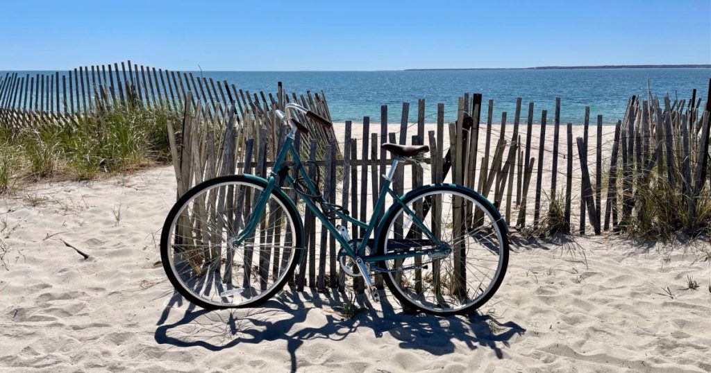 Bike leaning against fence by beach
