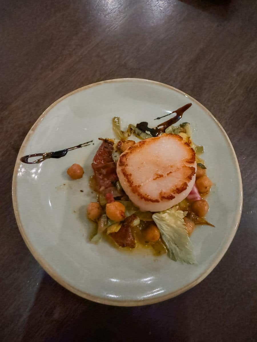 Large scallop on plate with chickpeas and lettuce