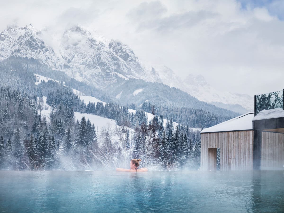 Naturhotel Forsthofgut outdoor pool and mountains at winter