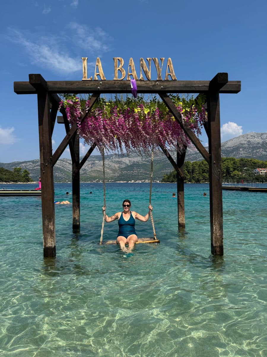 Tamara on swing in water at La Banya beach club on Korcula