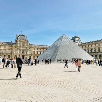 Louvre Museum glass pyramid with people walking