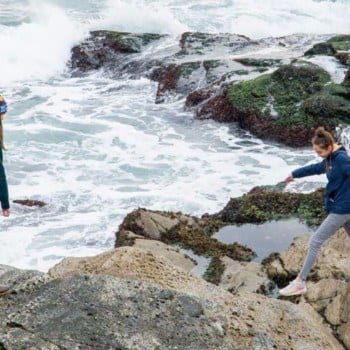 woman and teen girl jumping on rocks at Beavertail State park